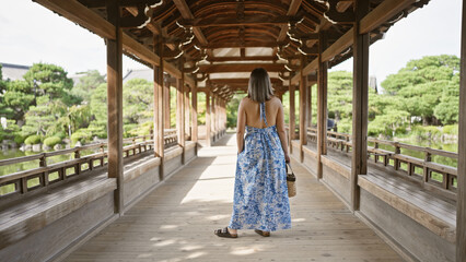 Portrait of a beautiful hispanic woman walking away, a back view of a casual walk at heian jingu,...