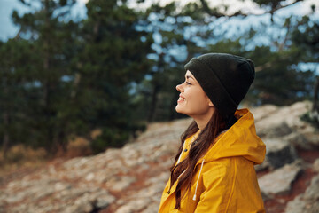 A fashionforward woman in a vibrant yellow raincoat and beanie gazes into the distance on a rainy...