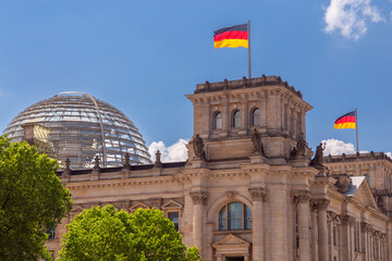 Glass dome and waving German national flags on the Reichstag building. Berlin.