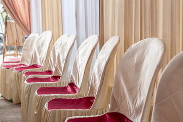 The cream and red colored wedding invitation guest decoration chairs were neatly lined up