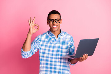 Photo of handsome confident guy wear plaid shirt texting modern gadget showing okey emtpy space isolated pink color background