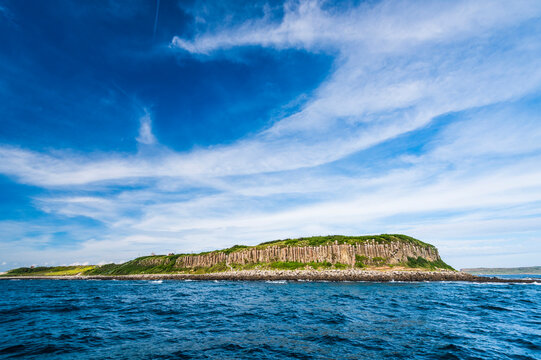 Beautiful view of Tongpan Island with a blue sky background in Penghu, Taiwan. The island is a basalt mesa landform with a shoreline of cliffs made of basalt columns.