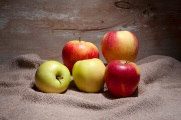 red and yellow apples, still life, fruit lying on material on a wooden background, rustic style