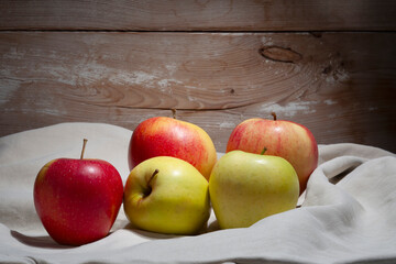 red and yellow apples, still life, fruit lying on material on a wooden background, rustic style