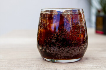 Cold cola with ice in a glass on the table
