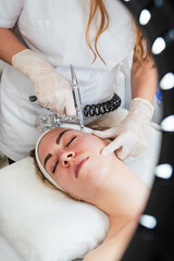 Beautiful young woman receiving oxygen jet peeling treatment. Modern and popular beauty or skincare...