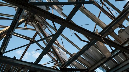 Close-up on a collapsed roof in an industrial building, exposed beams and sky view. 