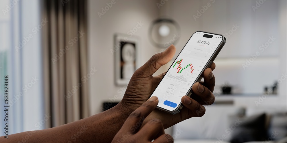 Wall mural a user interacts with a stock trading app on a smartphone, displaying market charts and data, in a m