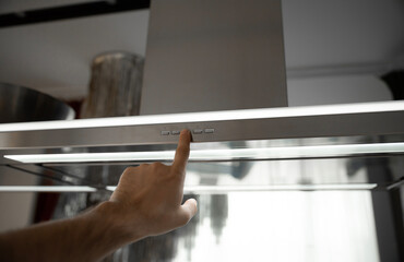 Human hand pushing the button of the kitchen range hood