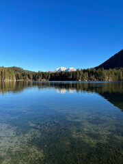 Lake Hintersee in Bavaria, Germany, with forested shoreline and the Alps in the background, showcasing serene and picturesque natural beauty