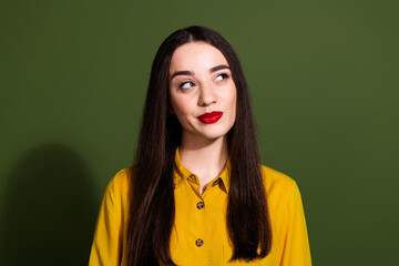 Photo of adorable doubtful girl wear yellow shirt looking empty space isolated green color background