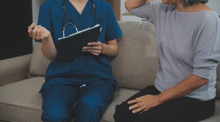 Female caregiver doing regular check-up of senior woman in her home.