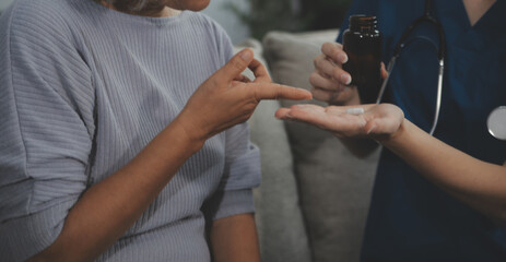 Female caregiver doing regular check-up of senior woman in her home.