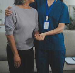 Female caregiver doing regular check-up of senior woman in her home.