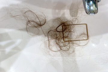 Close up reveals a sink covered in strands of hair, creating a messy and unhygienic sight.