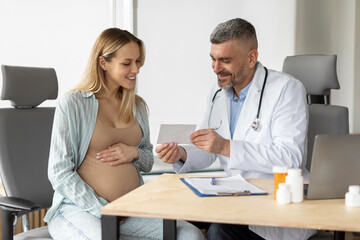 Doctor with European pregnant woman during medical consultation in gynecological office. Medical...