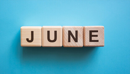 Wooden blocks with word JUNE on blue background. Summer time. Flat lay. Close-up.