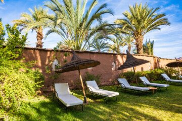 Sunchairs in luxury lodge hotel tropical garden near Agdz town in Atlas Mountains, Morocco, North...