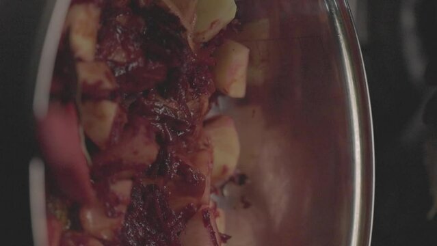 Closeup slow-motion of adding Bay laurel to vegetables in a cooking pot and stirring with red spoon