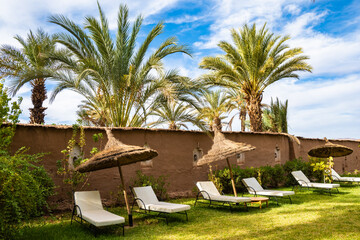 Sunchairs in luxury lodge hotel tropical garden near Agdz town in Atlas Mountains, Morocco, North...