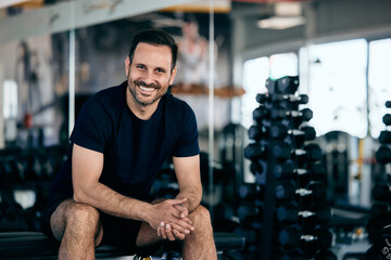 Portrait of a strong man, smiling for the camera while training at the gym.