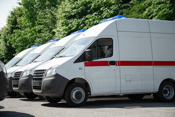 Multiple new  white ambulance vans parked near a hospital