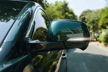 Closeup image of mirror of electric car on road in front of house