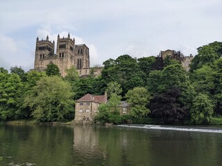 Durham, UK - July 25th 2021: The magnificent Durham Cathedral, viewed over the River Wear in the city of Durham in the UK. This was during the Covid 19 pandemic on a cloudy summer day.