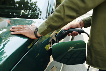 Owner taking plug out of socket after charging his EV