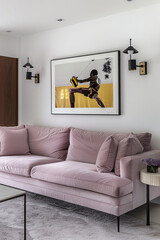 A framed artwork of an athlete in midb area hanging on the wall above sofa, with light purple velvet fabric and black metal legs, placed against a white wall.The room also features minimalist lighting