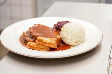 The cook prepares a dish of fried meat and cabbage and pours sauce over it.