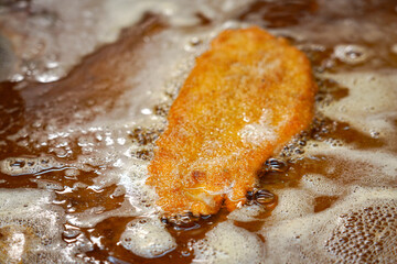 Fried schnitzel on the stove in the kitchen of a restaurant before serving the dish.