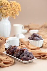 Dates in white dish on a beige background.