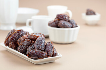 Dates in white dish on a beige background.