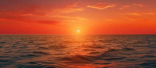 Fototapeta premium Idyllic sunset captured over the sea waters, displaying warm orange and red hues in a picturesque copy space image.