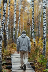 A person walking down a narrow wooden path surrounded by trees, possibly hiking or exploring