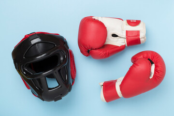 Boxing helmet and gloves on color background, top view.
