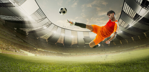 Focus and determination. Young man, soccer player in orange uniform hitting ball in jump during...