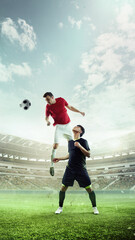 Vertical image of two men, soccer players in motion, opponents on field competing for victory on outdoor arena. 3D stadium. Concept of sport, competition, tournament, games, event