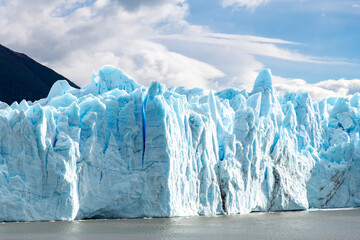 Glacier wall of the white and blue colored terminus of the Perito Moreno Glacier in bright sun near...