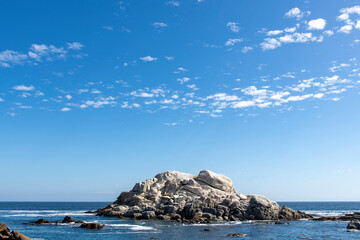 Panoramic view of the colorful rock in nature preserve Penon de Vida Marina, Valparaiso, Chile with ocean in background against a blue sky known for colonies of sea lions and birds
