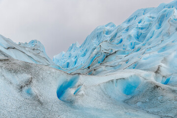 Glacier surface of  white and blue colored ice and dust, volcanic ash or soot particles deposited...