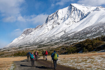 Fototapeta premium Torres del Paine National Park, Patagonia, Chile; hikers walking towards the lookout point for the three iconic granite towers (torres) on the W-trek route surrounded by snow covered mountains