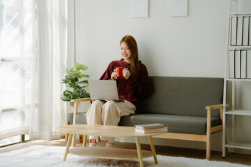 A woman is sitting on the sofa with a girlfriend's mug in her hand. She is smiling and she is...