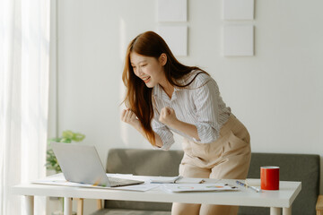 Adorable businesswoman holding coffee cup while working in the office room.