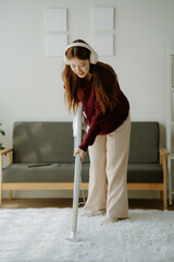 House cleaning with fun. Happy young asian housewife singing her favorite song during cleanup,...