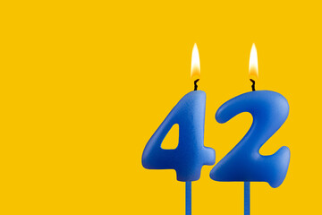 Blue birthday candle on yellow background - Number 42