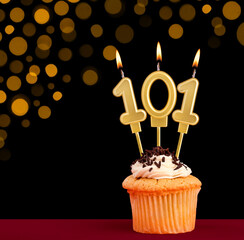 Birthday candle with cupcake - Number 101 on black background with out of focus lights