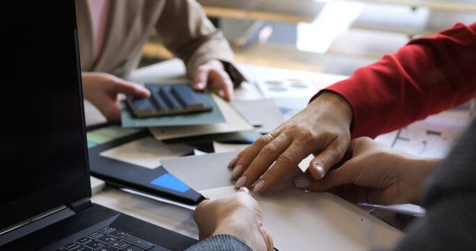 Creative session with fashion designers selecting fabric swatches. Team collaboration on color choices and textile planning. Professionals brainstorm innovative patterns and material selections.