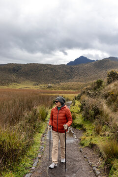 Adult woman enjoying a mountain hike, escaping the city noise, wearing a waterproof jacket, wool hat, and sunglasses, looking to the side